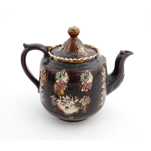 169 - A Victorian Measham bargeware teapot decorated with a basket of flowers, berries, and foliage. Appro... 