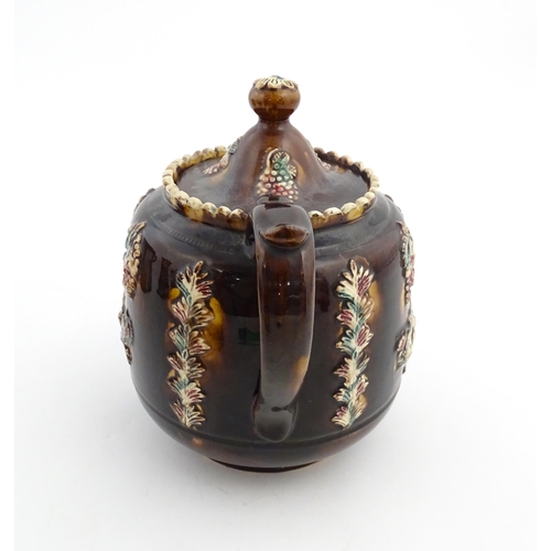 169 - A Victorian Measham bargeware teapot decorated with a basket of flowers, berries, and foliage. Appro... 