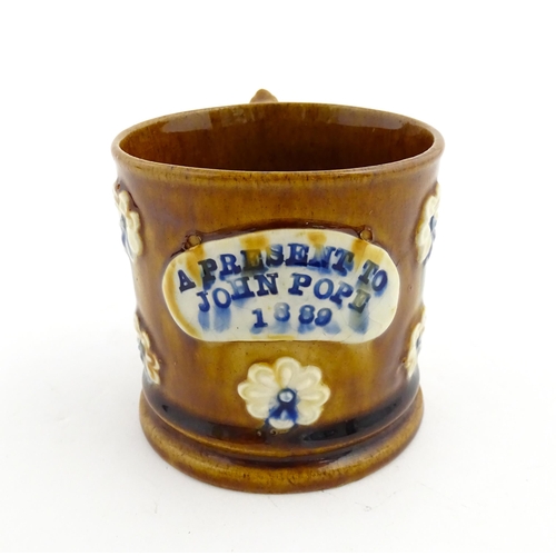 173 - A Victorian Measham bargeware mug decorated with flowers and bearing plaque titled A Present to John... 