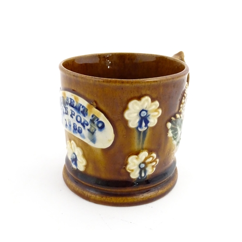 173 - A Victorian Measham bargeware mug decorated with flowers and bearing plaque titled A Present to John... 