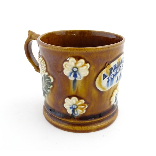 173 - A Victorian Measham bargeware mug decorated with flowers and bearing plaque titled A Present to John... 