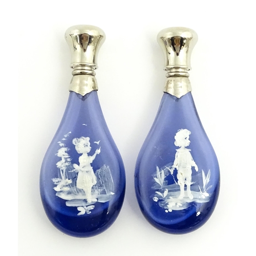 216 - Two 20thC blue glass perfume / scent bottles / flasks with Mary Gregory style decoration and white m... 