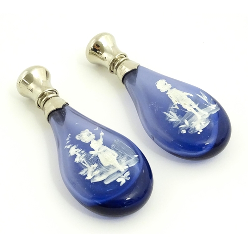 216 - Two 20thC blue glass perfume / scent bottles / flasks with Mary Gregory style decoration and white m... 