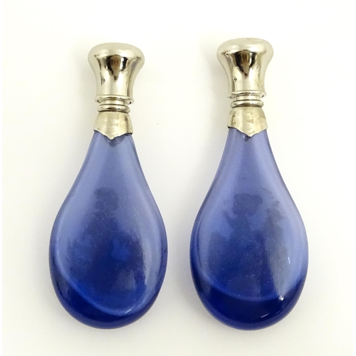 216 - Two 20thC blue glass perfume / scent bottles / flasks with Mary Gregory style decoration and white m... 