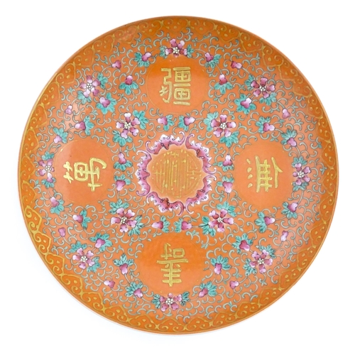 3 - A Chinese plate / dish with orange ground decorated with Character marks and scrolling floral and fo... 