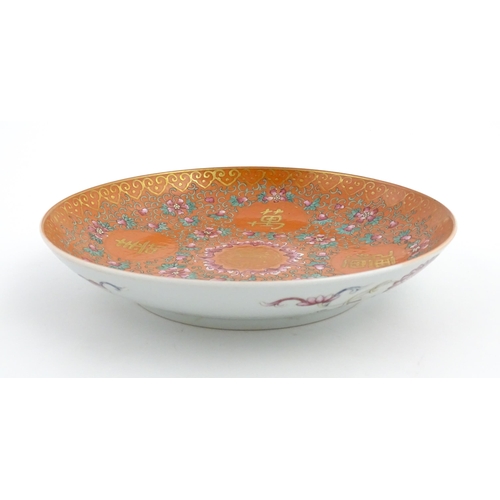 3 - A Chinese plate / dish with orange ground decorated with Character marks and scrolling floral and fo... 