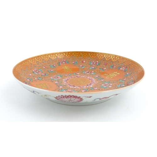 3 - A Chinese plate / dish with orange ground decorated with Character marks and scrolling floral and fo... 