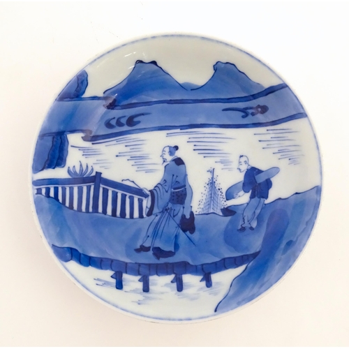 33 - A Chinese blue and white plate / dish decorated with figures on a bridge with lake and mountains bey... 