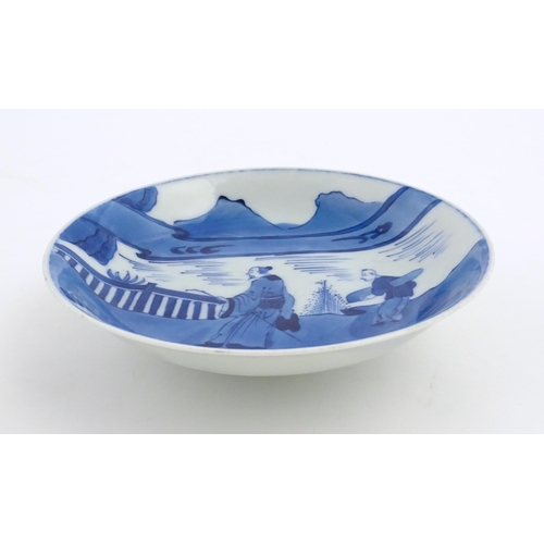 33 - A Chinese blue and white plate / dish decorated with figures on a bridge with lake and mountains bey... 