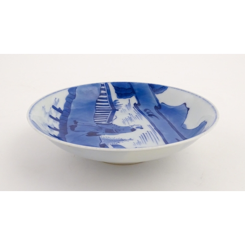 33 - A Chinese blue and white plate / dish decorated with figures on a bridge with lake and mountains bey... 