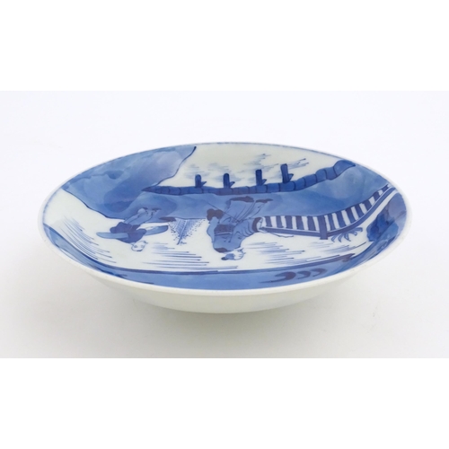 33 - A Chinese blue and white plate / dish decorated with figures on a bridge with lake and mountains bey... 