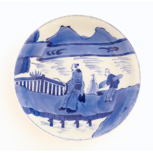 33 - A Chinese blue and white plate / dish decorated with figures on a bridge with lake and mountains bey... 