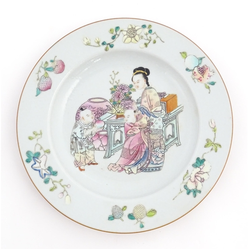 46 - A Chinese famille rose plate decorated with a lady and two children, with flowers and vase, bordered... 