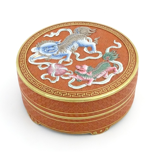 47 - A Chinese box of circular form with foo dog / guardian lion detail, with gilt border. Character mark... 