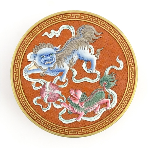 47 - A Chinese box of circular form with foo dog / guardian lion detail, with gilt border. Character mark... 