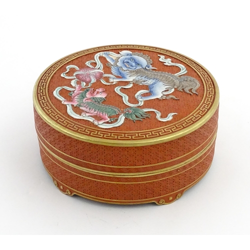 47 - A Chinese box of circular form with foo dog / guardian lion detail, with gilt border. Character mark... 