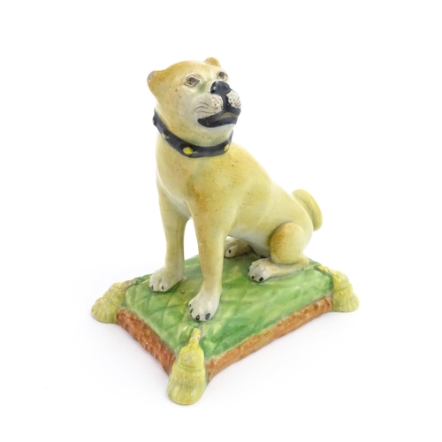 55 - A 19thC model of a Pug dog seated on a green tasselled cushion. Approx. 4 1/2