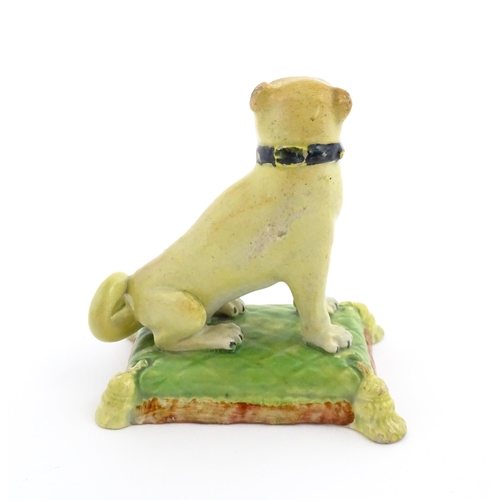 55 - A 19thC model of a Pug dog seated on a green tasselled cushion. Approx. 4 1/2