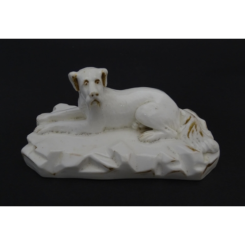 58 - A 19thC porcelain model of a recumbent Great Dane dog on a rocky base, with gilt highlights. Possibl... 