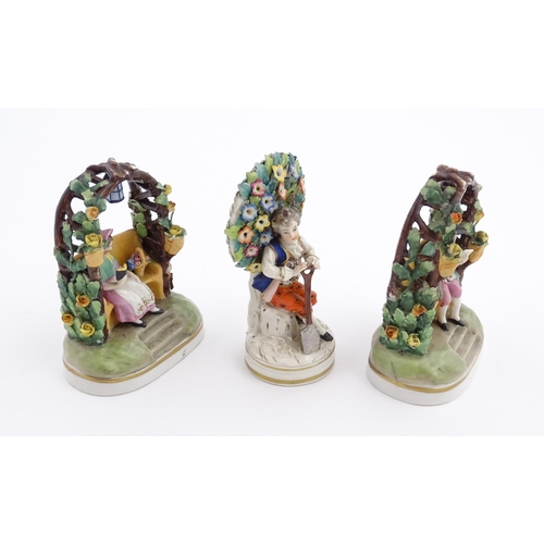 62 - A pair of porcelain figures models of a seated man and woman reading under a flower arch with lanter... 