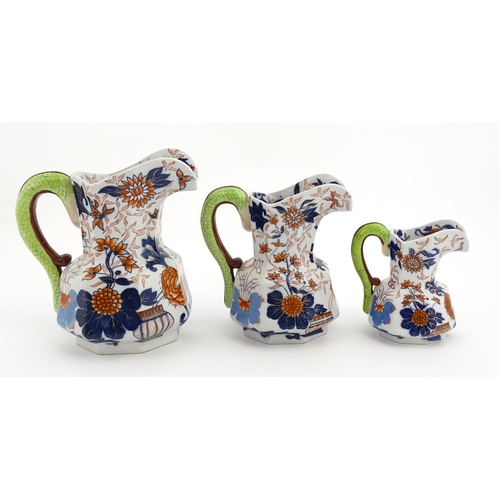 71 - A graduated set of three Ringtons tea merchants ironstone china advertising jugs with floral and fol... 