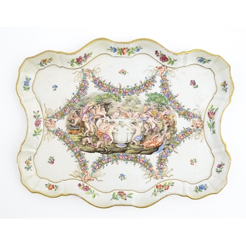 73 - A Capodimonte style tray of shaped form decorated in relief with a Bacchanalian dining scene bordere... 