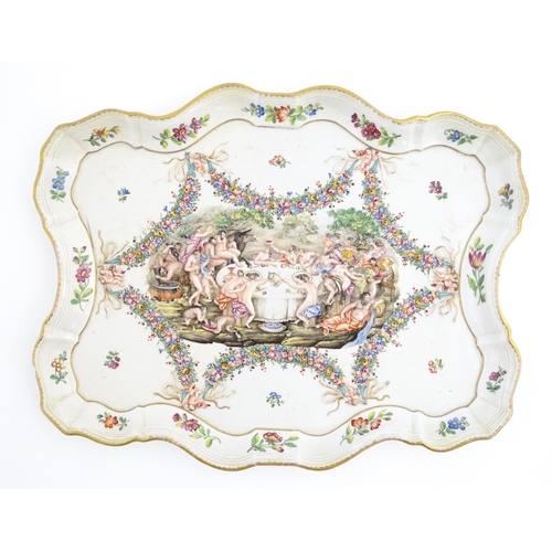 73 - A Capodimonte style tray of shaped form decorated in relief with a Bacchanalian dining scene bordere... 