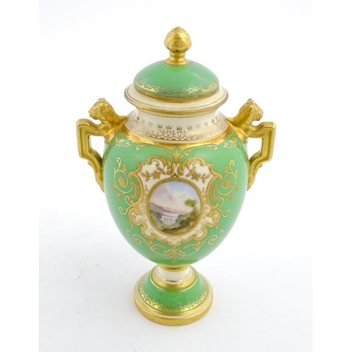 85 - A Coalport urn and cover with twin lion head handles, the green ground decorated with hand painted v... 