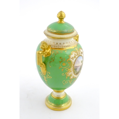 85 - A Coalport urn and cover with twin lion head handles, the green ground decorated with hand painted v... 