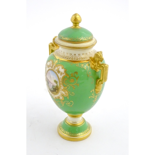 85 - A Coalport urn and cover with twin lion head handles, the green ground decorated with hand painted v... 