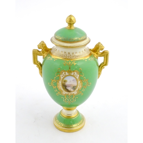 85 - A Coalport urn and cover with twin lion head handles, the green ground decorated with hand painted v... 