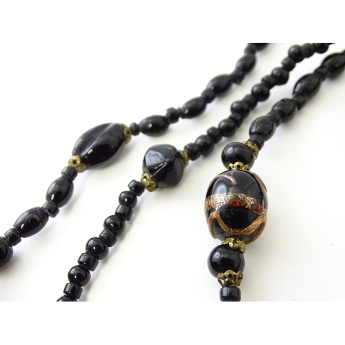 771 - A black bead necklace, some beads with gold stripe detail. Approx. 59