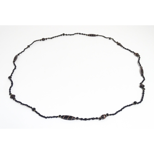 771 - A black bead necklace, some beads with gold stripe detail. Approx. 59