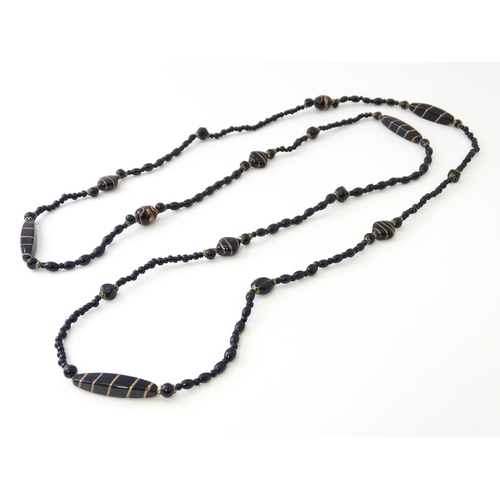 771 - A black bead necklace, some beads with gold stripe detail. Approx. 59