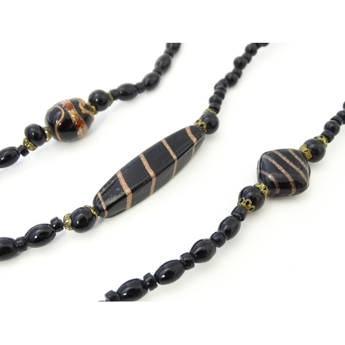 771 - A black bead necklace, some beads with gold stripe detail. Approx. 59