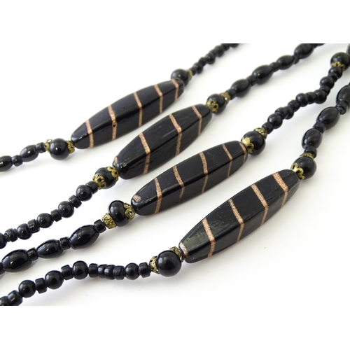 771 - A black bead necklace, some beads with gold stripe detail. Approx. 59