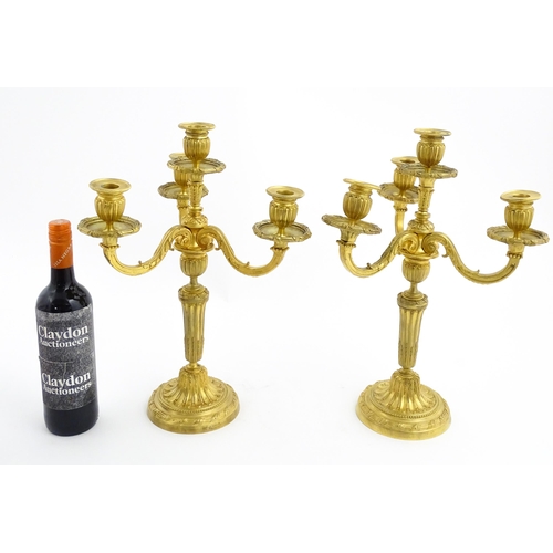 1025 - A pair of early 20thC French gilt bronze candelabra / candelabrum in the Louis XVI style, with three... 