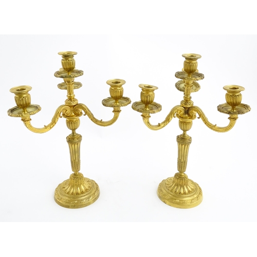 1025 - A pair of early 20thC French gilt bronze candelabra / candelabrum in the Louis XVI style, with three... 