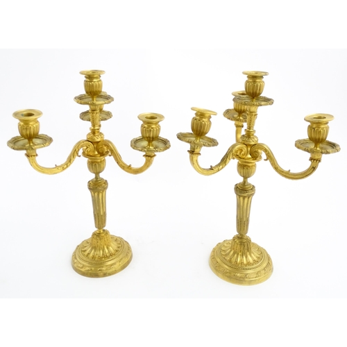 1025 - A pair of early 20thC French gilt bronze candelabra / candelabrum in the Louis XVI style, with three... 