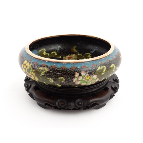 1039 - A Chinese cloisonne bowl, the black ground with floral and foliate decoration. Character marks under... 