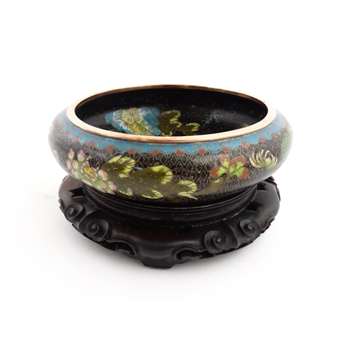 1039 - A Chinese cloisonne bowl, the black ground with floral and foliate decoration. Character marks under... 