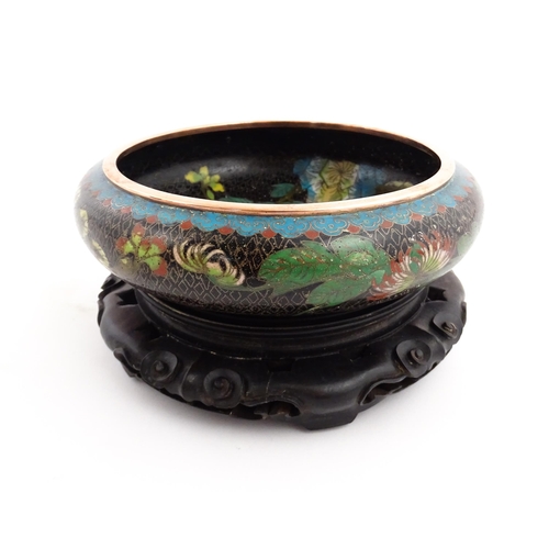 1039 - A Chinese cloisonne bowl, the black ground with floral and foliate decoration. Character marks under... 