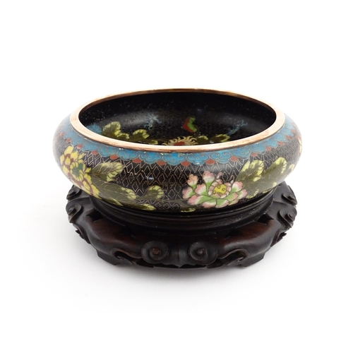 1039 - A Chinese cloisonne bowl, the black ground with floral and foliate decoration. Character marks under... 