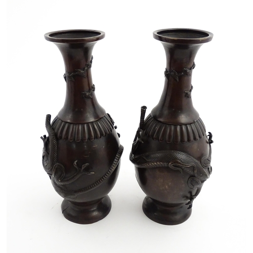 1041 - A pair of Chinese cast vases with flared rims decorated with relief dragon decoration, the necks wit... 