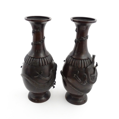 1041 - A pair of Chinese cast vases with flared rims decorated with relief dragon decoration, the necks wit... 