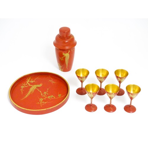 1044 - An Oriental Art Deco style red lacquer cocktail set, comprising six cocktail glasses, a cocktail sha... 