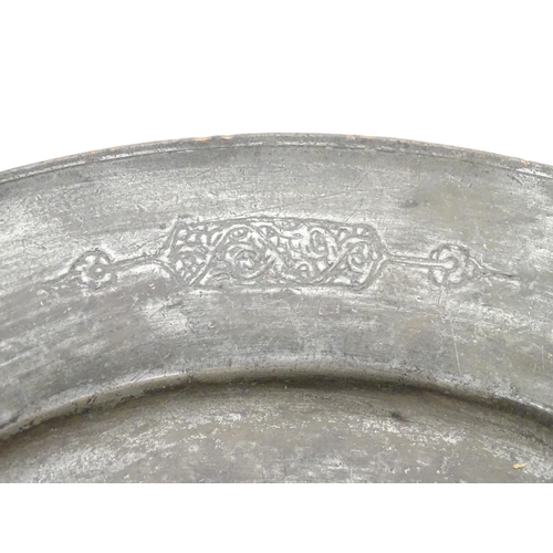 1048 - An Islamic metal charger with incised fish decoration to centre and scrolling motifs to border. Appr... 