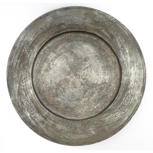 1048 - An Islamic metal charger with incised fish decoration to centre and scrolling motifs to border. Appr... 