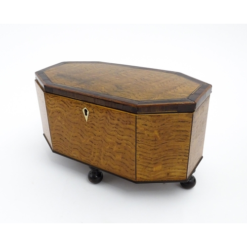 1220 - A 19thC tea caddy of octagonal form with crossbanded rosewood top raised on four feet, opening to re... 