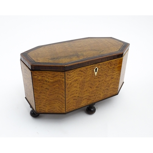 1220 - A 19thC tea caddy of octagonal form with crossbanded rosewood top raised on four feet, opening to re... 